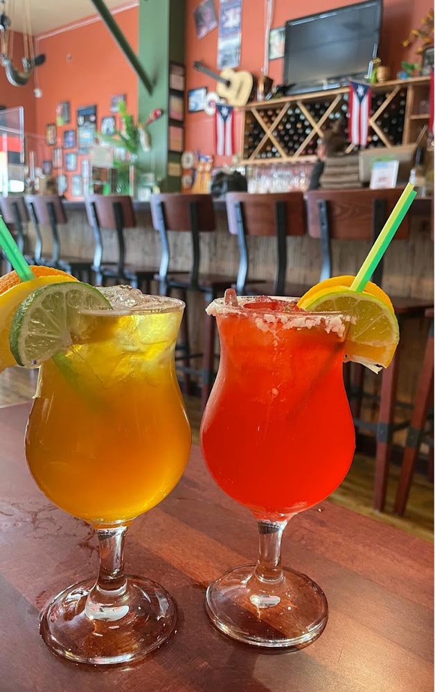two drinks on a table with garnishes and straws