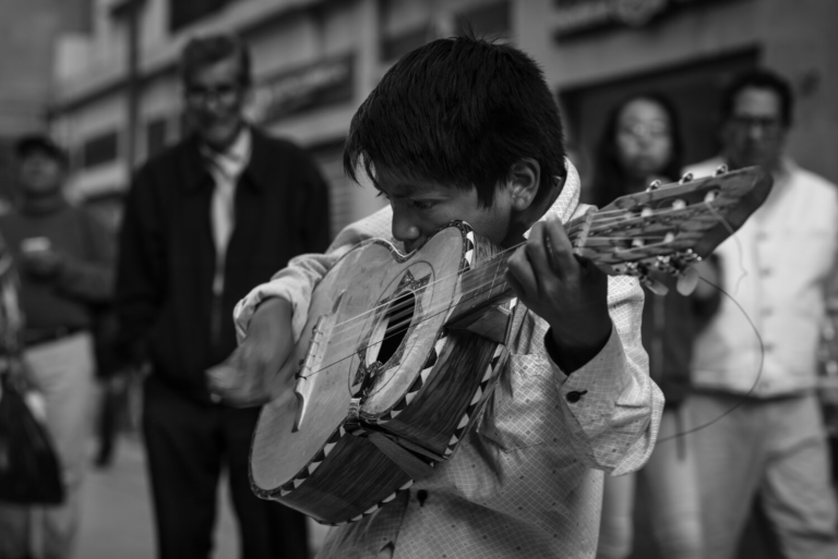 photo of young boy focused on playing guitar
