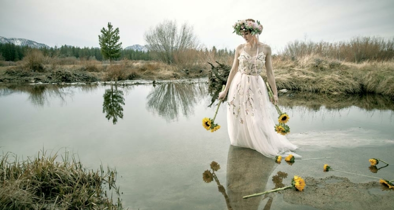 Woman wading in water holding sunflowers