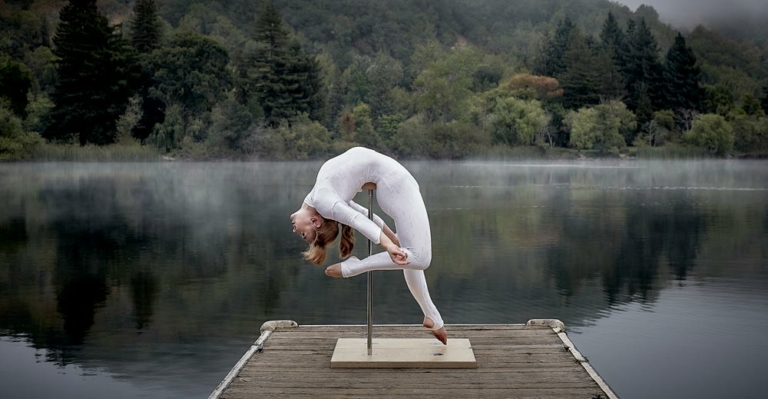 acrobat posing in front of misty lake
