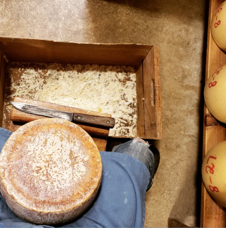 round of cheese being shaved