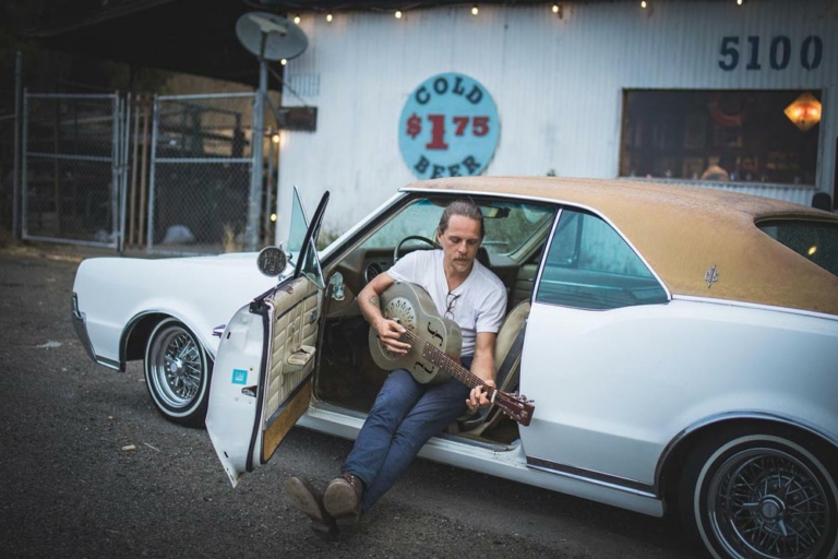 man playing guitar sitting in old car