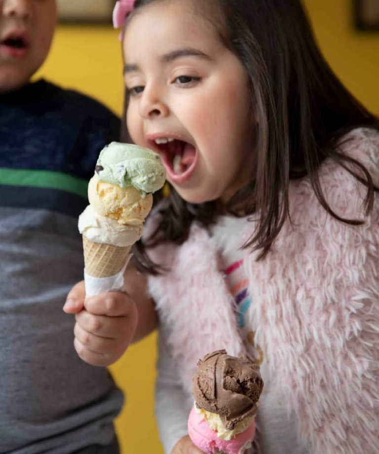 girl about to bite into triple scoop icecream