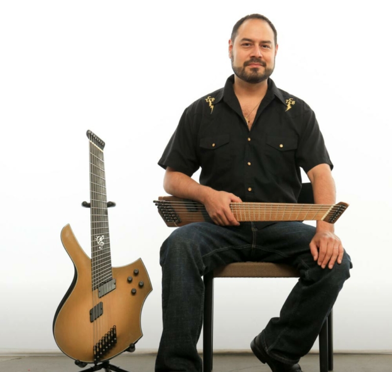 Nate lopez seated with 2 guitars, white background